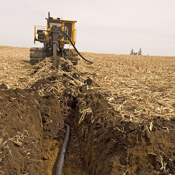 Tiling machine installing plastic drainage tile in Iowa farmland.